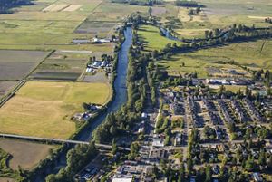 Aerial view of a residential area alongside a river surrounded by farm fields.