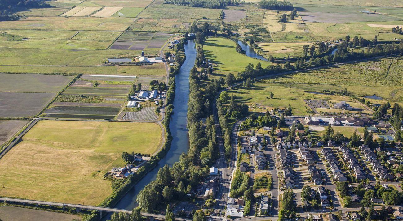 Aerial view of a residential area alongside a river surrounded by farm fields.
