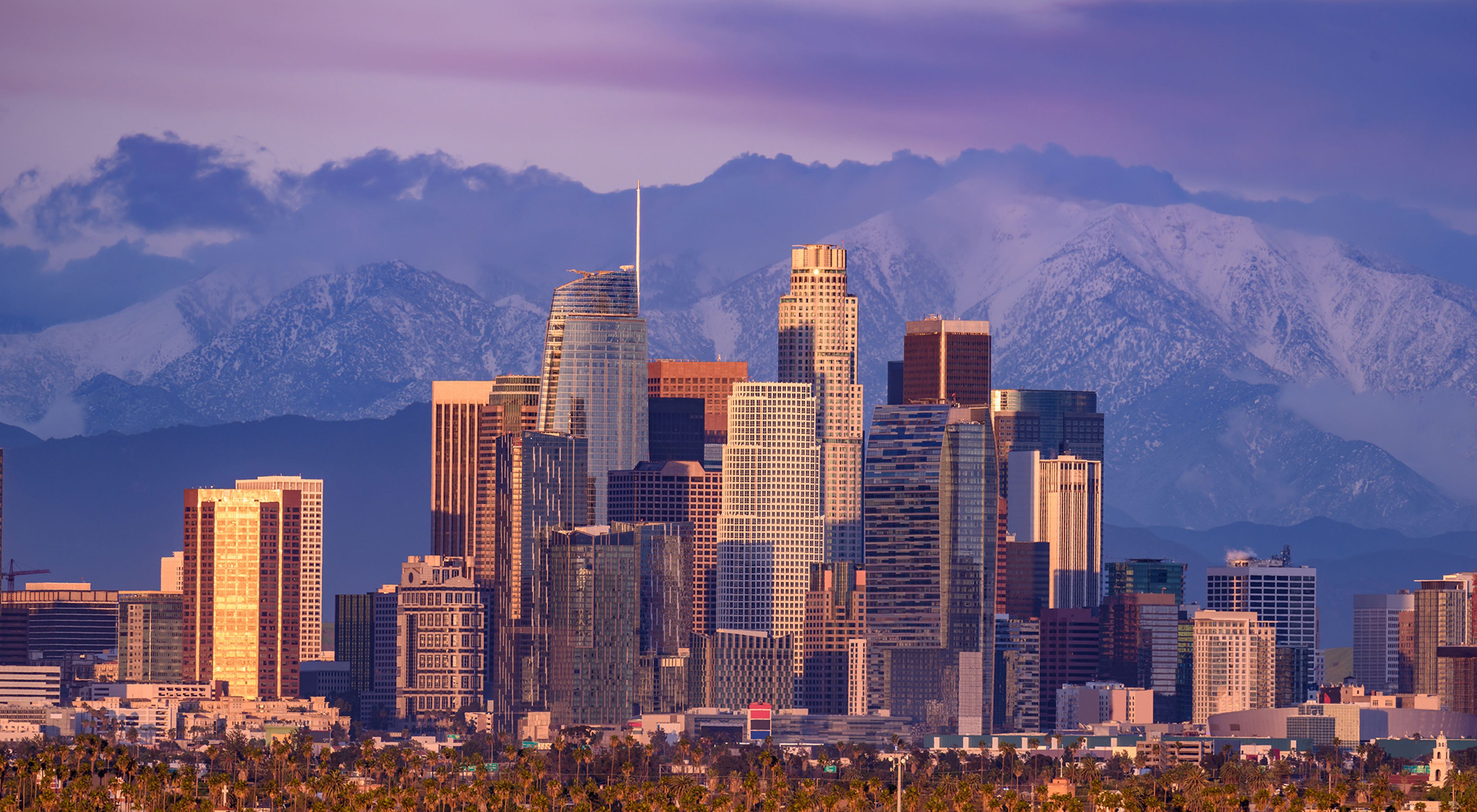 Skyline of Los Angeles against a backdrop of snowcapped mountains.