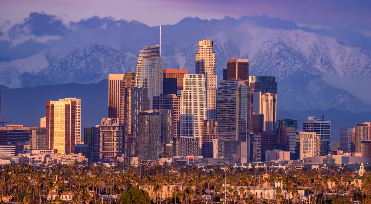 Skyline of Los Angeles against a backdrop of snowcapped mountains.