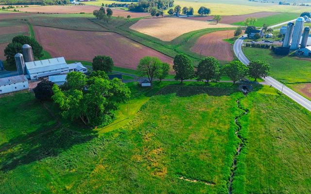 An aerial view of a coast farm with green fields and a white barn.