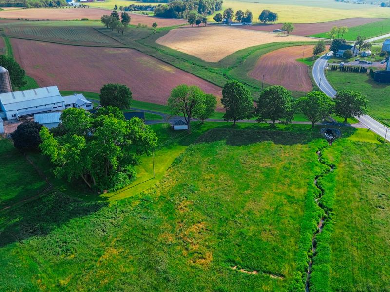 An aerial view of a coast farm with green fields and a white barn.