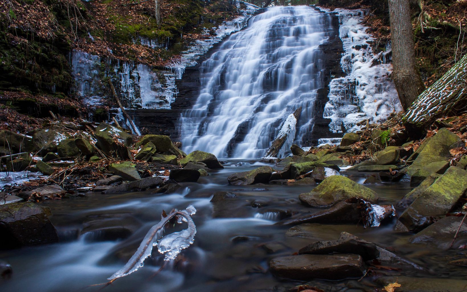 View of waterfall and creek with a light dusting of snow on surrounding rocks.