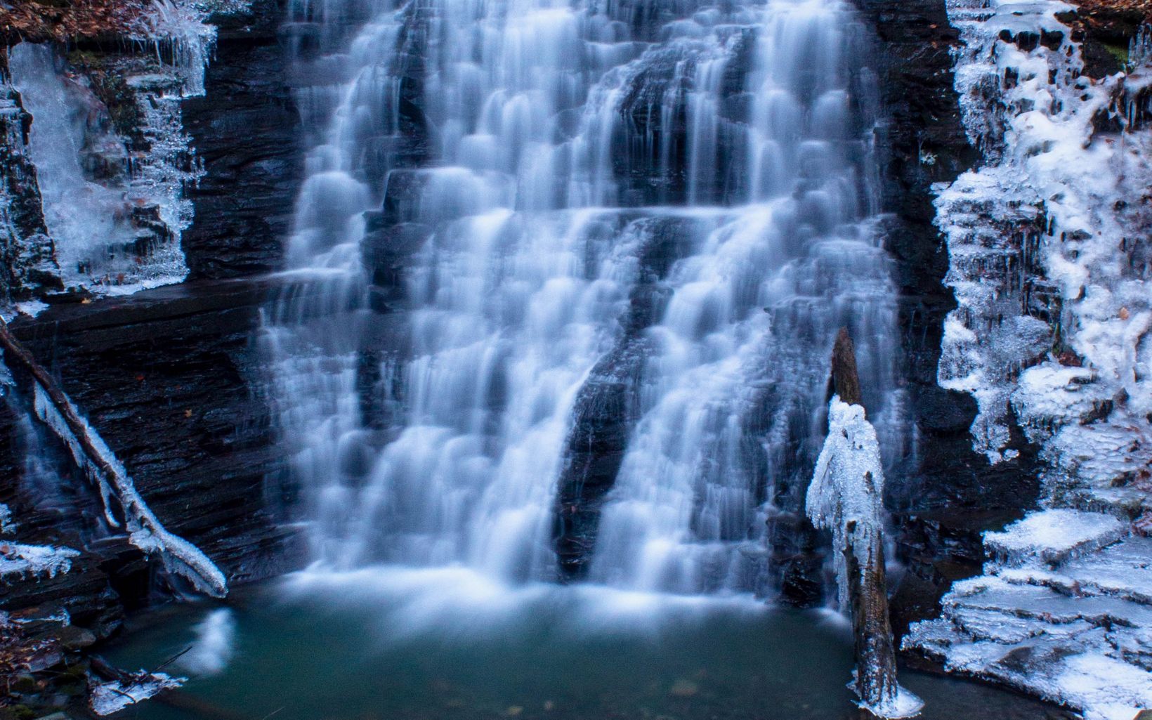 Waterfall with frozen ice on surrounding rocks.