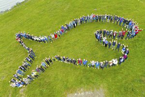 An aerial view of people forming a fish-shaped line.