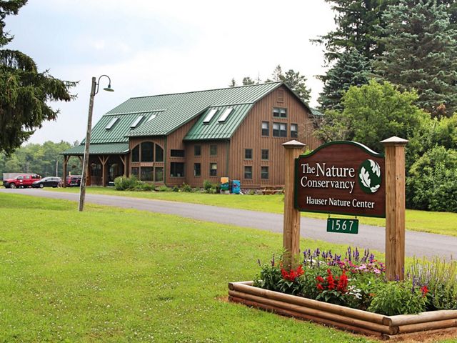 A large sign reading The Nature Conservancy Hauser Nature Center welcomes visitors to the large, rustic TNC office in the background.