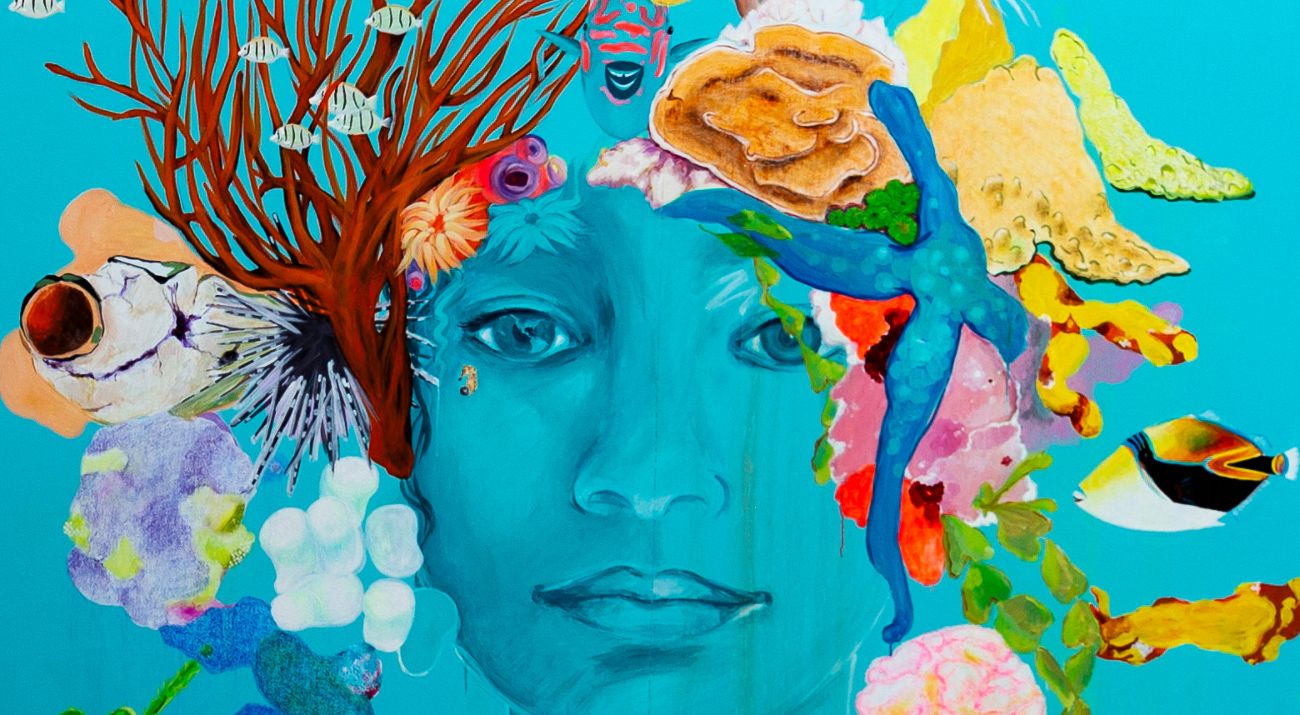 A bright turquoise mural of a woman's face with sea creatures as hair.