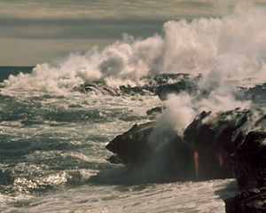 Molten lava flows into the sea creating clouds of steam at Hawai'i Volcanoes National Park.