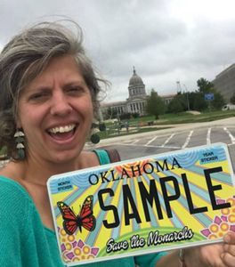 Woman holding specialty monarch license plate.
