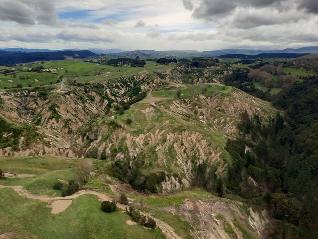 Aerial view of steep hillsides cut with channels and steep dropoffs due to erosion.