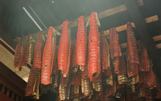 Docenas de tiras de salmón ahumado cuelgan de un techo de madera