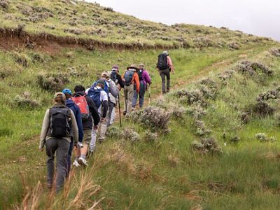 A line of hikers treks up a dirt path.