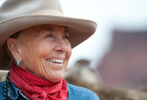 A woman in a western hat looking into the distance.
