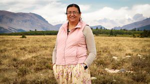A woman standing on a vast prairie smiling at the camera.