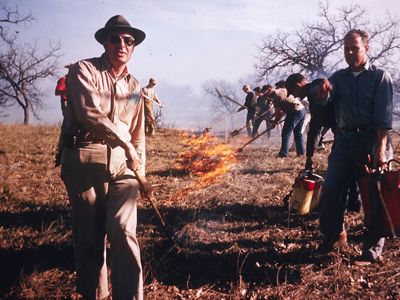 Historic photo of several men tending to a fire in a prairie.