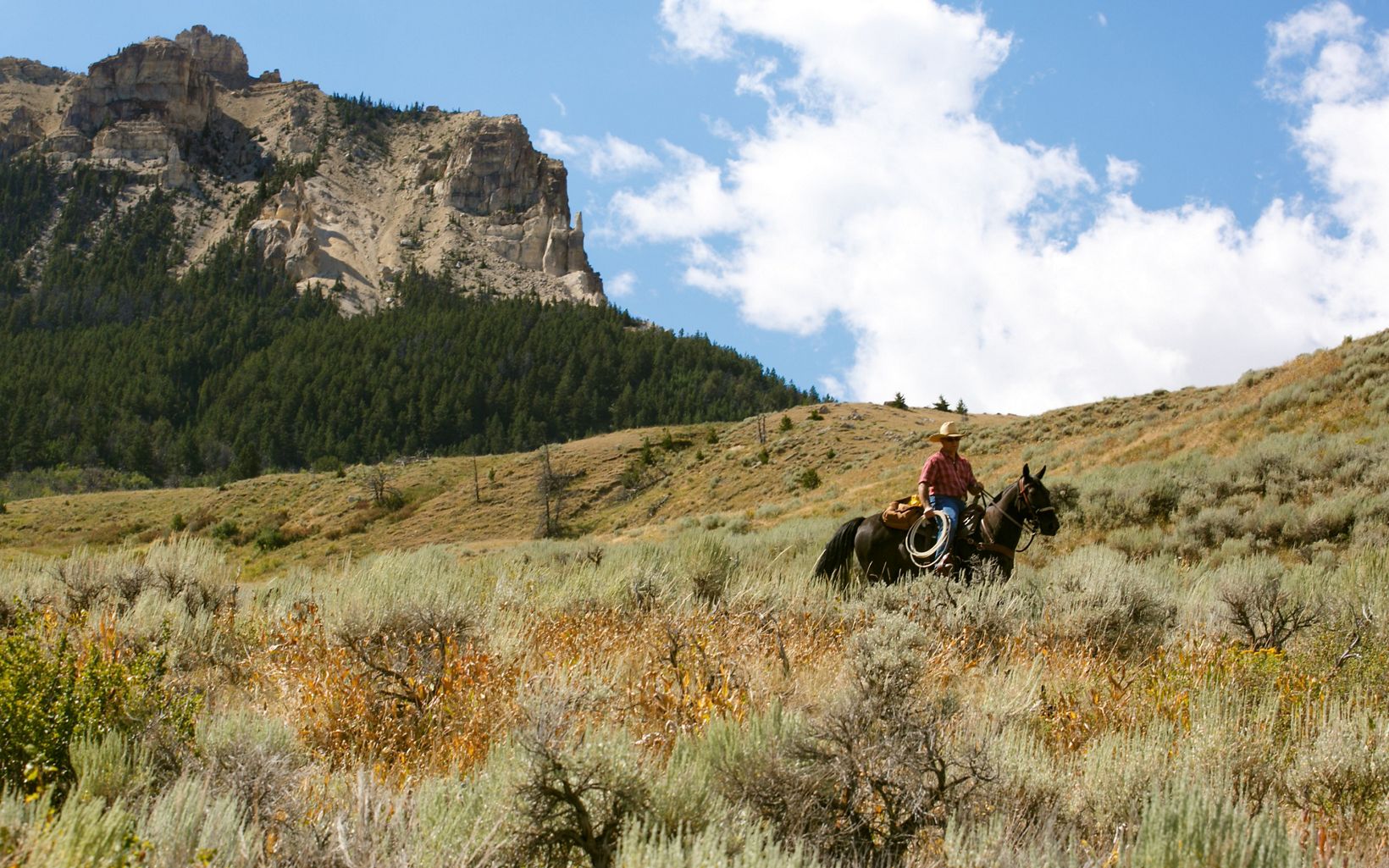 Person on horseback riding up a mountain.