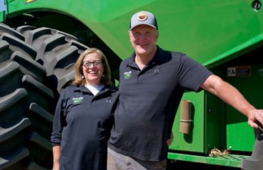 Two farmers standing in front of a tractor.
