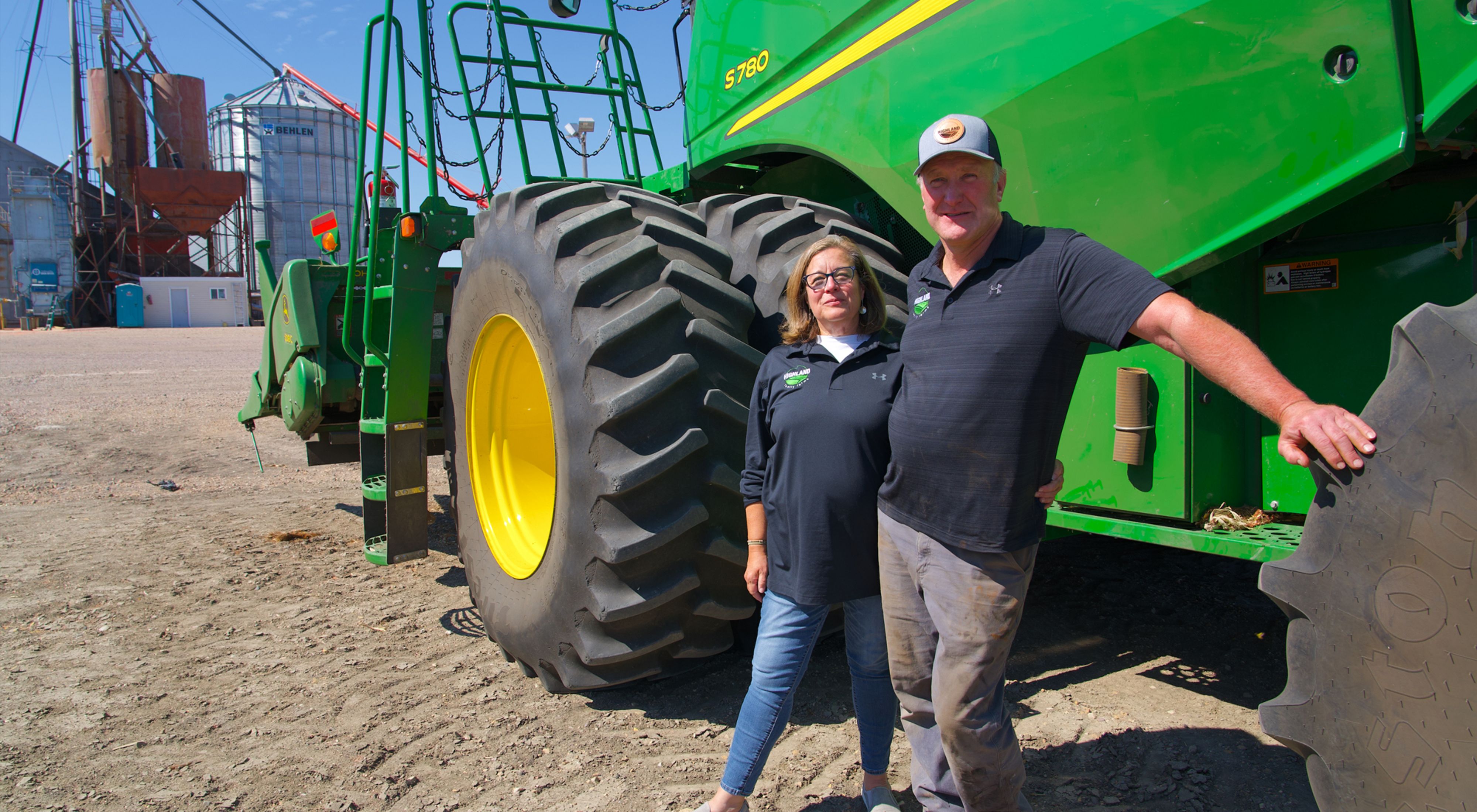 Two farmers standing in front of a tractor.