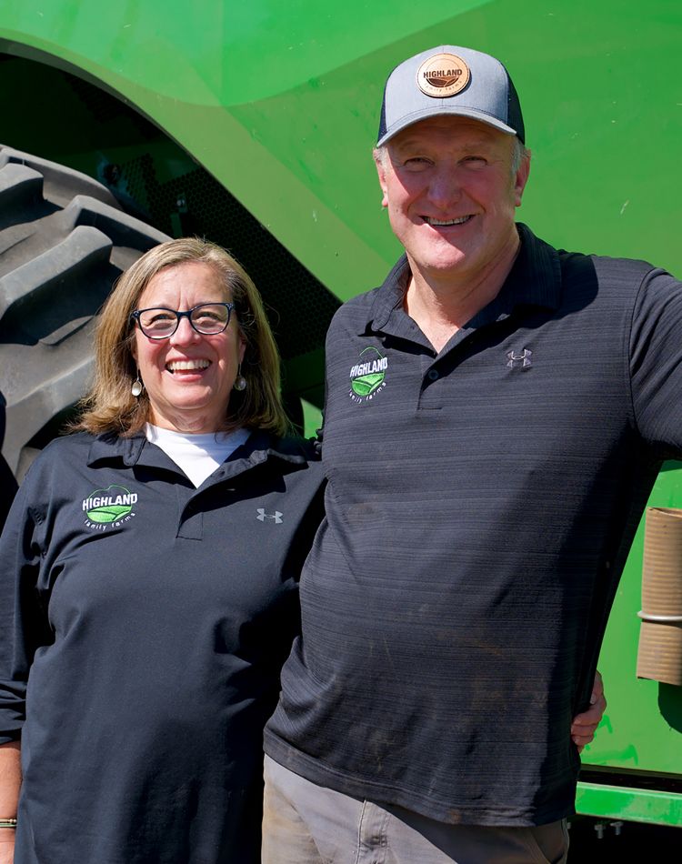 woman and man stand in front of a green tractor
