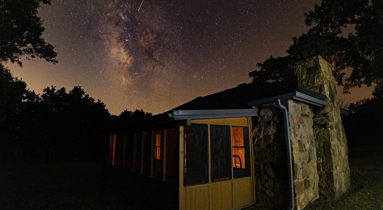 The cabin of John Joseph Mathews frames the Pawhuska night sky.