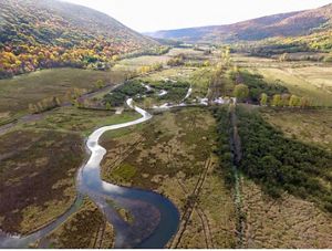 An aerial view of a stream winding through a mountain valley.
