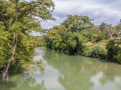 A blue river lined with dense trees.
