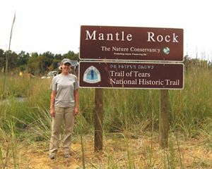 A staff member stands next to the Mantle Rock sign.