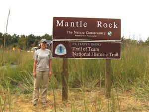 A staff member stands next to the Mantle Rock sign.