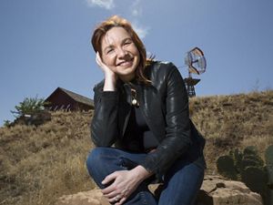 Katharine Hayhoe sitting in a dry landscape under a blue sky.