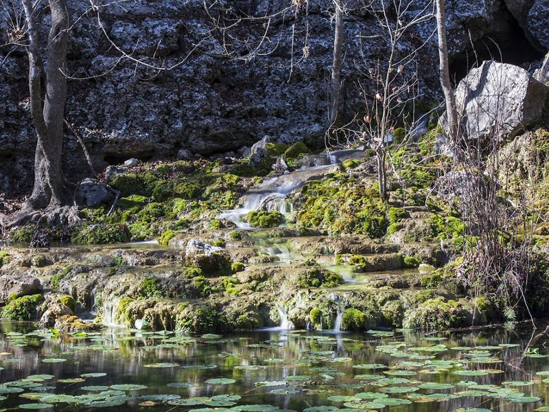 Water falls over stacked rocks into a creek.