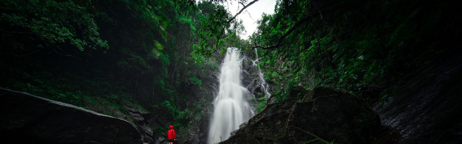 A person stands in front of a magnificent waterfall.