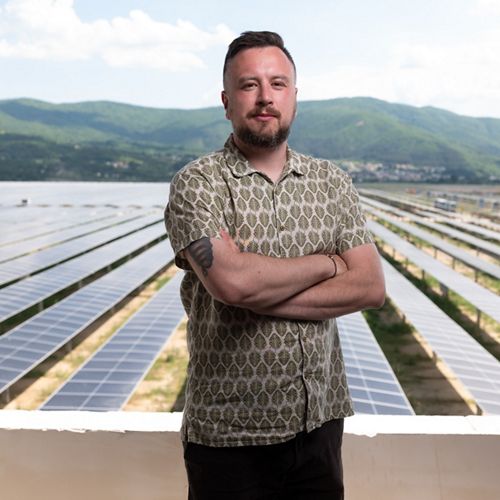 A man stands in front of a solar power field.