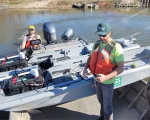 Three men stand next to two semiautonomous kayaks resting on a research boat.