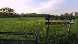 A sign is situated in a grassy field.