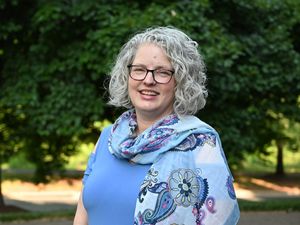 Candid portrait of Bramble Klipple standing in front of dark green trees.