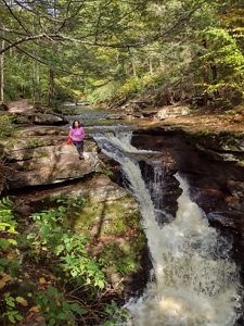 Diana Oviedo Vargas sits on a rock fixture next to a small waterfall.