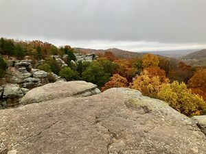 Autumn forest and rolling countryside viewed from a ledge of sandstone cliffs.