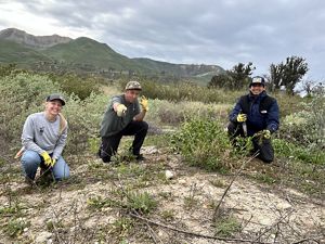 Three volunteers on the Santa Clara River Preserve smile at the camera.