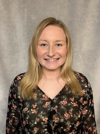 Headshot of Katelyn smiling admist gray backdrop.