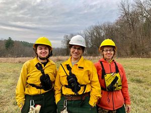 Three women wearing yellow fire gear stand together.