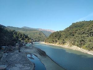 Dense forests line either side of a wide river in India.