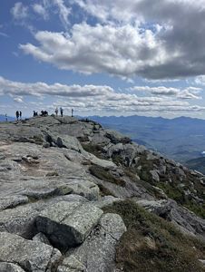 A group of hikers enjoy a view from a rocky mountain ridgetop. 