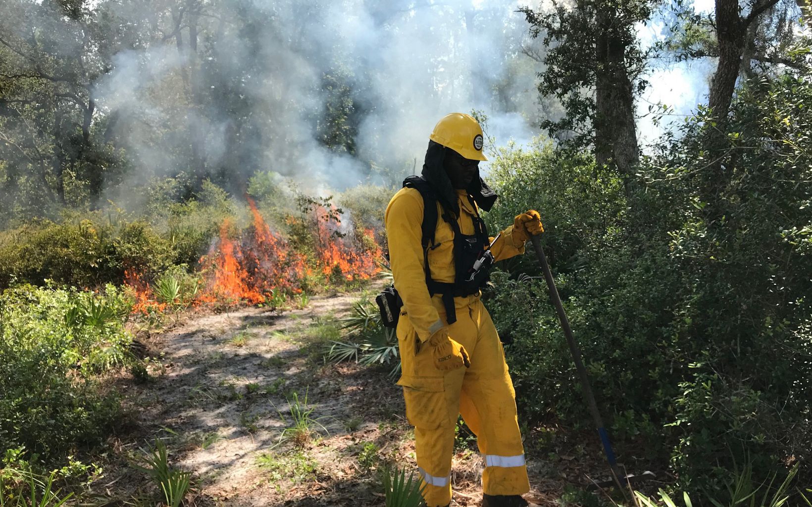 A prescribed fire practitioner from the Bahamas monitors the fire in Florida.