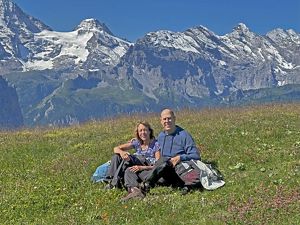 Dr. Ken Robbins &  Dr. Tana Burkert in a field with mountains behind them. 