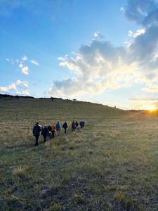 Group of hikers hiking across a vast grassland.