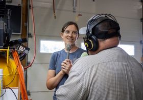 Two people standing and talking on microphones.
