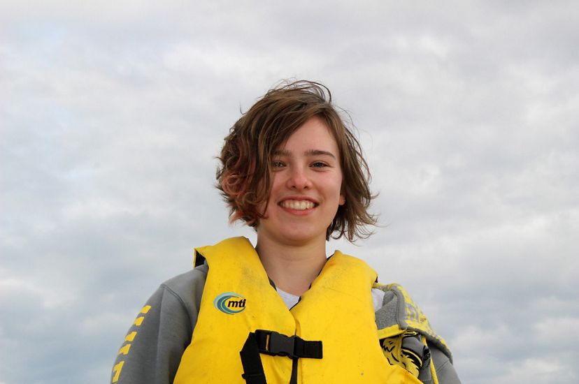 A smiling woman wearing a yellow life jacket.