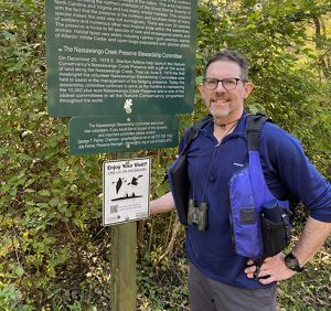 Steve Volkers stands next to a green information sign at Nassawango Creek Preserve.