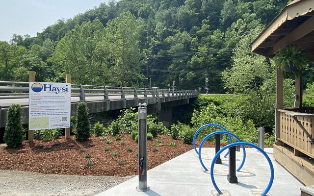 Three blue bike racks next to a wooden gazebo and a riverwalk in Haysi, VA.