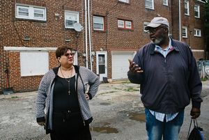 Shirley Irizarry and Kevin Barfield stand in an alley and talk to each other.